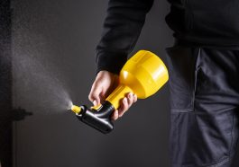 Close-up of a person using a yellow pest control sprayer to manage pests.